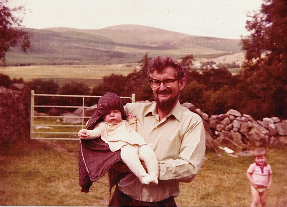 Brian Winder holding a baby in the countryside